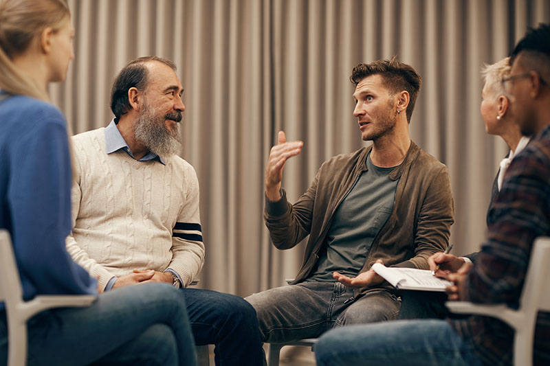 A group of people talk at a support group